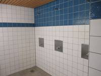 gekachelter Duschbereich mit 3 Duschplätzen, der obere Duschbereich ist dunkel gekachelt, der untere hell