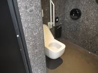 Eine weiße Toilette mit einem Haltegriff an der einen Seite