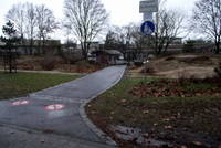 asphaltierter Fahrradweg abwärts, Abzweigung rechts zu Schulhof, hier 2 künstliche Engstellen