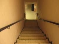 gerade Treppe die nach unten führt, etwa in der Mitte ein Podest, rechts und links je ein Handlauf