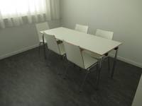 weißer Tisch mit 5 Stühlen in einem Raum mit schwarzem Boden