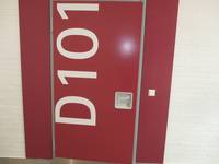 rote Tür mit einer großen weißen Beschriftung D101 und senkrechter Griffstange