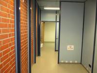 Flur durch einen Durchgang und eine offenstehnde Tür , links Mauerwerk, rechts blaue Trennwände