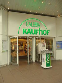 2 zweiflügelige Eingangstüren, über den Türen ist der Schriftzug "Galeria Kaufhof" vor den Türen ein Werbeaufsteller mit Broschüren 