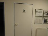 weiße Tür mit einem dunklem Rahmen und Rollstuhlsymbol darauf