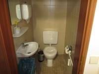 deckenhoch gekachelter Raum mit Standtoilette und Waschbecken