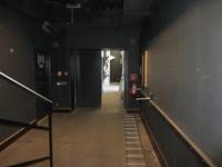 Flur bei Bühne, dann zweiflügelige, offenstehende Tür, im Vordergrund liegt eine Leiter 