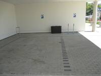 Zwei Behindertenparkplätze in einem überdachten Bereich. An der Wand sind Schilder angebracht