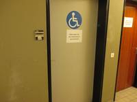 Eine Tür mit einem dunklen Türrahmen. Auf der Tür ist ein Rollstuhlsymbol