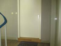 Eine weiße Tür in einer grauen Wand. Vor der Tür ist eine Stufe/Schwelle