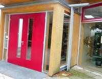 Rote zweiflügelige Eingangstür in einem vorgesetzten Gebäudeteil