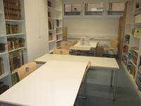 Ein Raum mit Tischen, Stühlen und Bücherregalen
