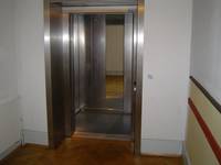 Aufzug mit offenstehender Metalltür; Spiegel in der Aufzugkabine