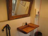 Ein Waschbecken aus Holz an einer gekachelten Wand mit Seifenspender, Papierhandtuchhalter und Spiegel