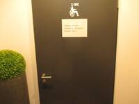 Eine dunkle Tür in einer hellen Wand. Auf der Tür ist ein Rollstuhlsymbol 