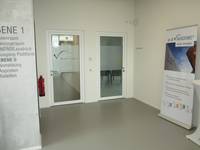 offener Raum mit zwei Glastüren, rechts ein großes Roll-up mit Informationen zur adViva-Akademie