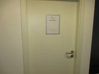 weiße Tür in weißer Wand, Schild "Seminarraum 2" mittig auf der Tür angebracht