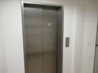 geschlossener Aufzug mit einer Metalltür, Taster an weißer Wand,rechts von der Tür