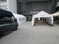 Ein Platz vor einem Gebäude mit zwei Zelten zwischen denen man durch kann