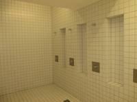 ein weiß gekachelter Raum mit drei Duschplätzen