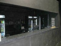 lange, massive Theke aus schwarzem Holz, schwache Beleuchtung, im Hintergrund Kühlschränke und Getränkekühlschränke