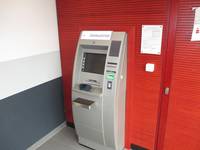 grauer Geldautomat, vor einer roten Wand