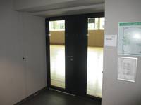 Zweiflüglige Tür mit eingesetzten Scheiben, dahinter die Sporthalle