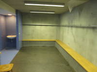 Raum mit Bänken und Gaderobenhaken, links offener blaugekachelter Bereich und ein weißes Waschbecken