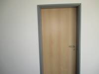Tür in heller Holzoptik mit dunkelgrauem Metallrahmen in weißer Wand