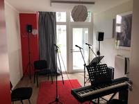 Ein Raum mit 3 Mikrofonen, einem Piano und zwei Stühlen