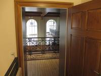 Nach der Treppe links der Eingang zur Empore; alte Holztür mit Metalldrücker, im Hintergrund Bogenfenster