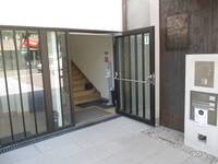 Eine offenstehende Glastür mit braunem Metallrahmen mit senkrecht verlaufenden Metallstreben als Einbruchschutz