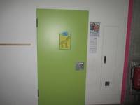 grüne Tür mit einem Tierbild, in einer hellen Wand