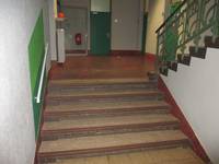 Treppe mit einem Handlauf links im Vordergrund, dahinter Stockwerk mit geschlossenen Türen 