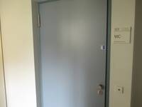 Eine graue Tür mit einem Schild rechts an der Wand