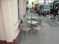 Vor dem Gebäude stehen 3 Tische mit Stühlen