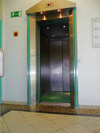 offener Aufzug, rechts am Eingang ist ein Ruftaster, rechts und links die Wand 