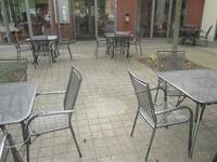 gepflasterte Terrasse mit grauen Metalltischen und Stühlen