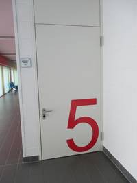 Weiße Tür an heller Wand, große rote Türbeschriftung: 5 
