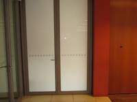 zweiflügelige Tür mit Milchglasscheibe, links davon eine Glastür, rechts davon eine rot gestrichene Wand