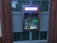 Im Fensterelement halbhoch aufgehängter Geldautomat in einem Edelstahlrahmen. 