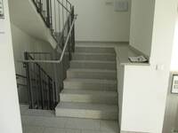 Eine gerade aufwärtsführende Treppe mit einem Handlauf links
