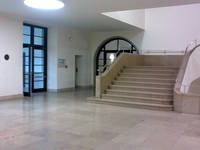 Steintreppe mit Podest Handläufen rechts und links, Treppe befindet sich im Foyer mit Natursteinplatten