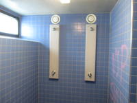 zwei blau gekachelte Duschplätze, links oben Fenster