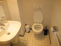 Ein weiße Toilette und ein weißes Waschbecken in einem weiß gekacheltem Raum