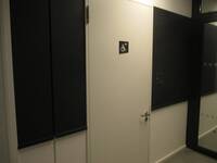 Eine weiße Tür mit Rollstuhlsymbol, links und rechts davon halbhoch dunkel verkleidete Wand