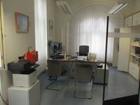 Ein Raum mit einem Schreibtisch, einem Kopiergerät und einigen Schränken