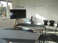 Ein Raum mit Tischen, Stühlen und einem großen Monitor.