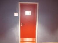 rote Tür mit Türschild vor einer Dunkeln Wand