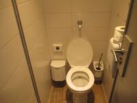 Eine weiße Toilette auf einem hellen Boden und an weiß gekachelten Wänden